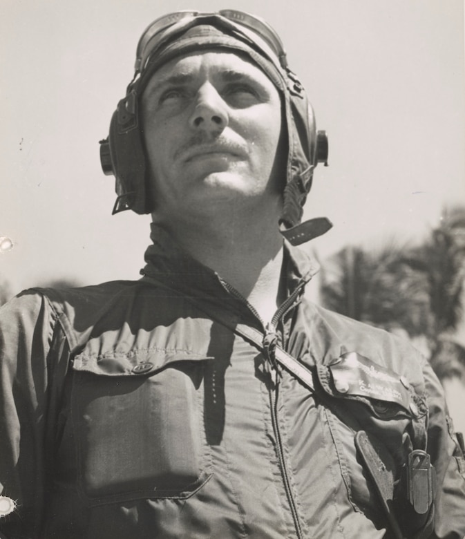 A Marine in an aviation helmet and goggles looks into the distance.