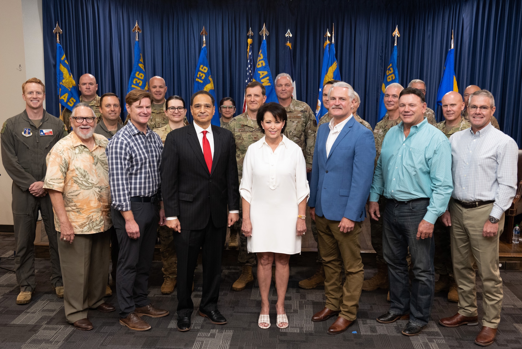 Group of men and women, civilian and military, standing on a stage.