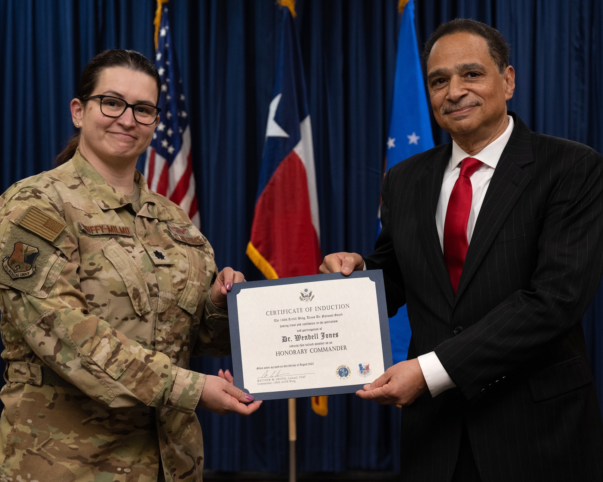 Two persons holding a flag, or certificate or shirt.