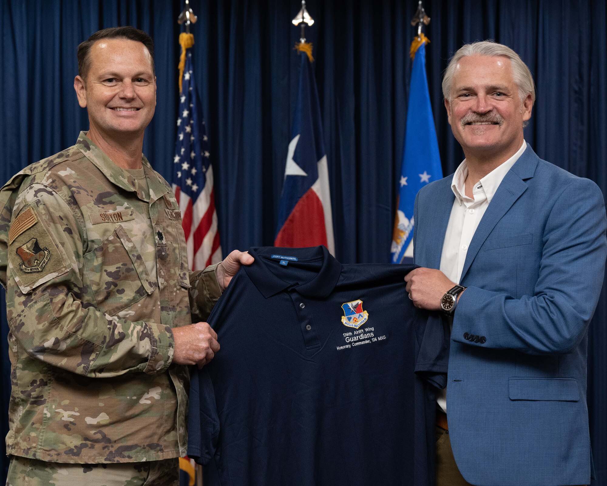 Two persons holding a flag, or certificate or shirt.