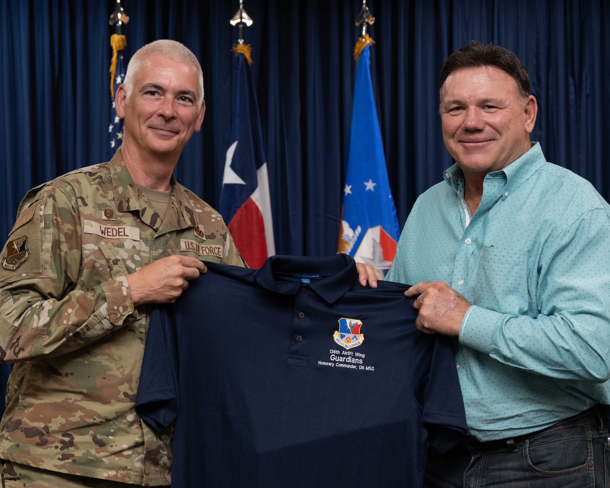 Two persons holding a flag, or certificate or shirt.