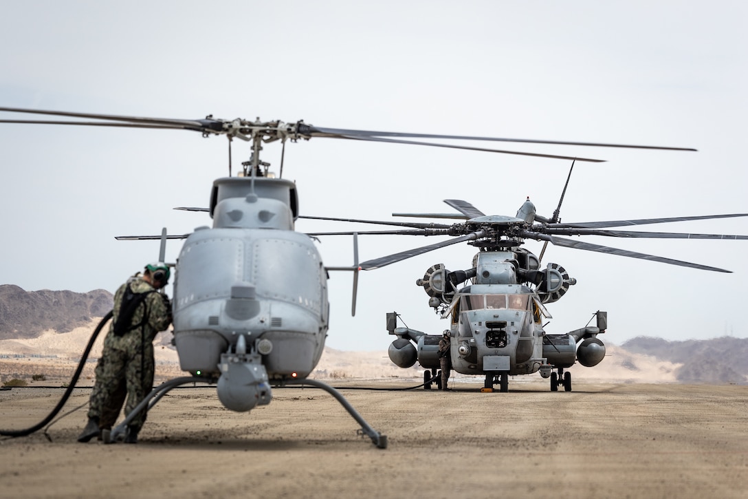 U.S. Marines with Marine Heavy Helicopter Squadron 361 (HMH-361), Marine Aircraft Group 16, 3rd Marine Aircraft Wing, and U.S. Navy Sailors assigned to Helicopter Sea Combat Squadron 21 (HSC-21), conduct a ground refuel for an MQ-8C Fire Scout during Service Level Training Exercise (SLTE) 5-23, at Camp Wilson, Marine Corps Air-Ground Combat Center, Twentynine Palms, California, July 31, 2023. SLTE is a series of exercises meant to prepare the Marine Air-Ground Task Force for quick and effective responses to military operations. The MQ-8C has shown its capabilities of operating from ship to shore with a mobile control station and the ability to refuel from expeditionary locations in support of the Marine Corps' mission. (U.S. Marine Corps photo by Lance Cpl. Richard PerezGarcia)