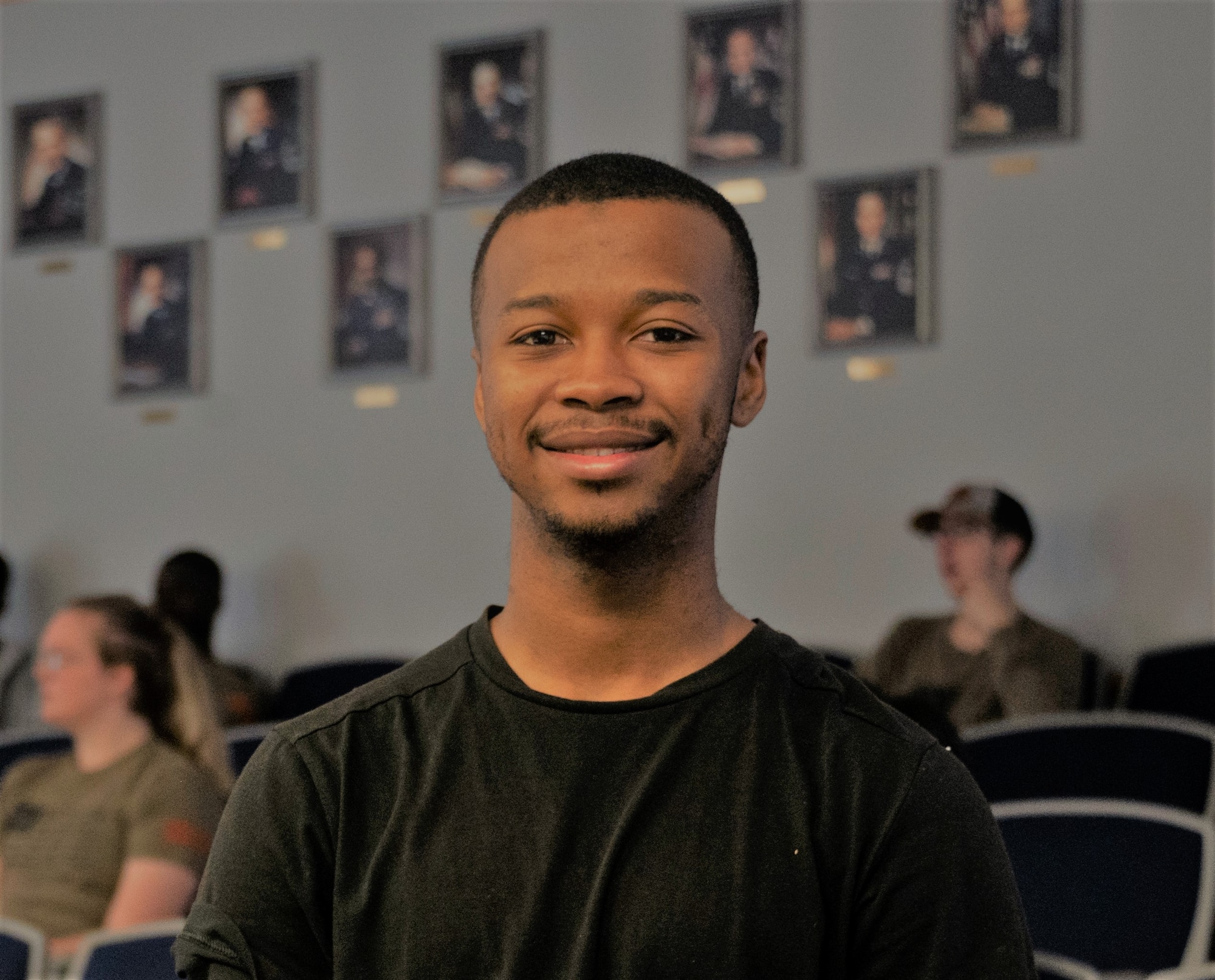 a young man stands in an auditorium school setting