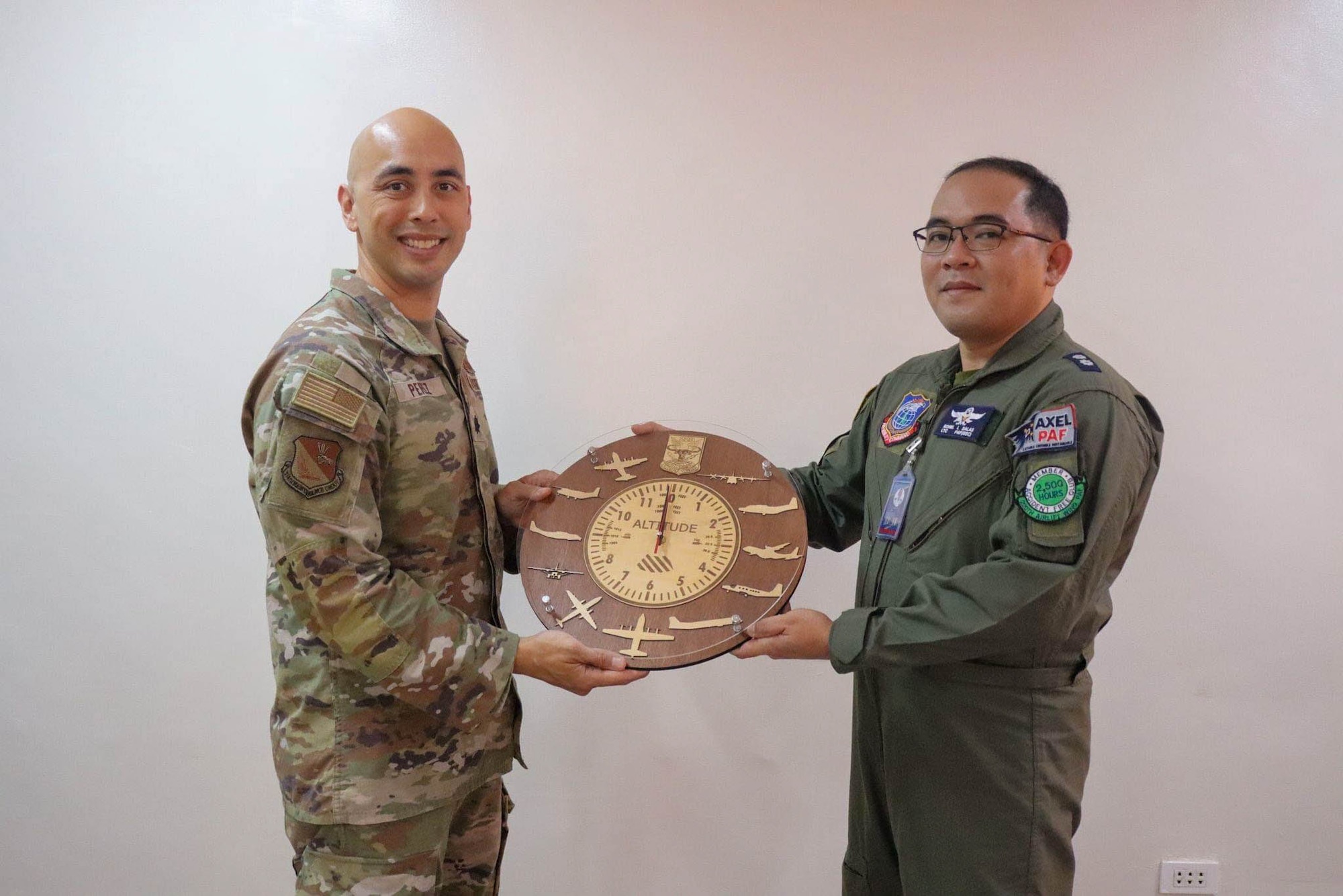 An American military member receives a clock from a Filipino service member.