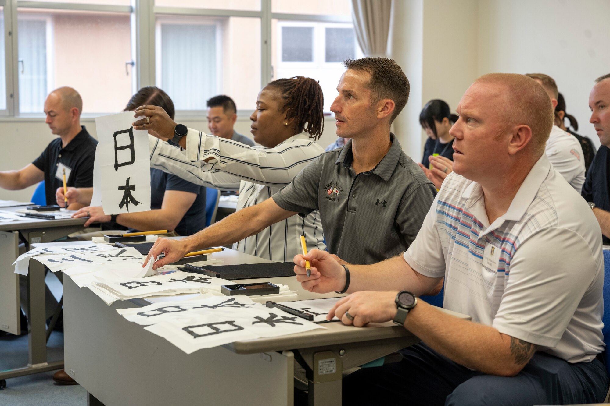 Commanders and senior enlisted leaders assigned to the 35th Fighter Wing practice calligraphy together during a team building event at the Misawa International Center.