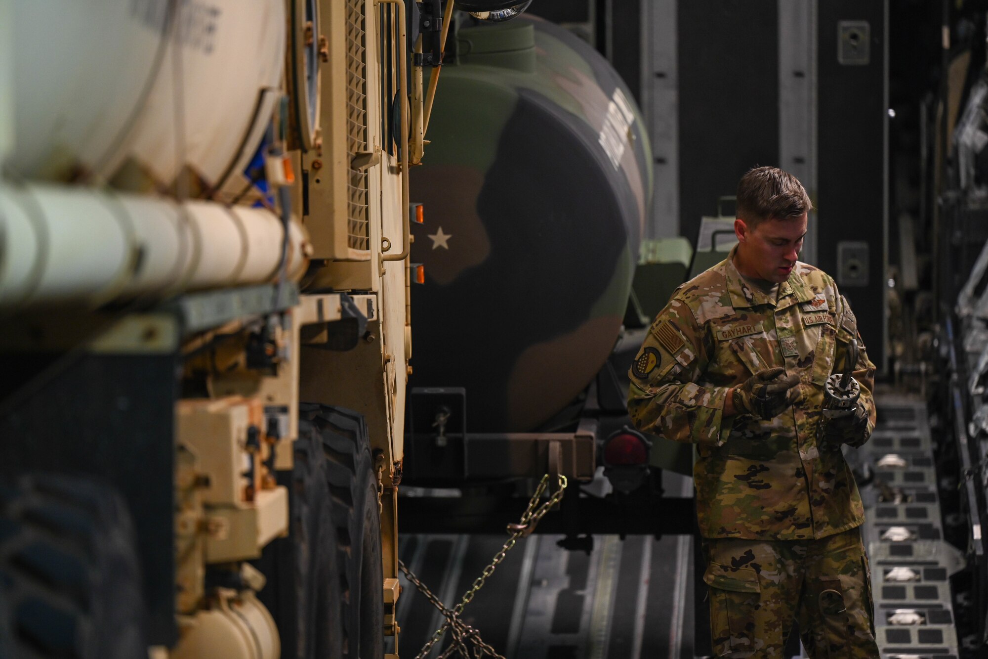 U.S. Air Force Tech. Sgt. Drew Gayhart, 535th Airlift Squadron loadmaster, secures a Heavy Expanded Mobility Tactical Truck on a C-17 Globemaster III in support of a Maui wildfire recovery humanitarian aid and disaster relief flight on the island of Maui at Joint Base Pearl Harbor-Hickam, Hawaii, August 19, 2023. Members from the 535th AS transported personnel and equipment from the U.S. Army in support of Joint Task Force 50 to provide humanitarian aid and assistance and offer continued support to the communities impacted by the wildfires. (U.S. Air Force photo by Senior Airman Makensie Cooper)