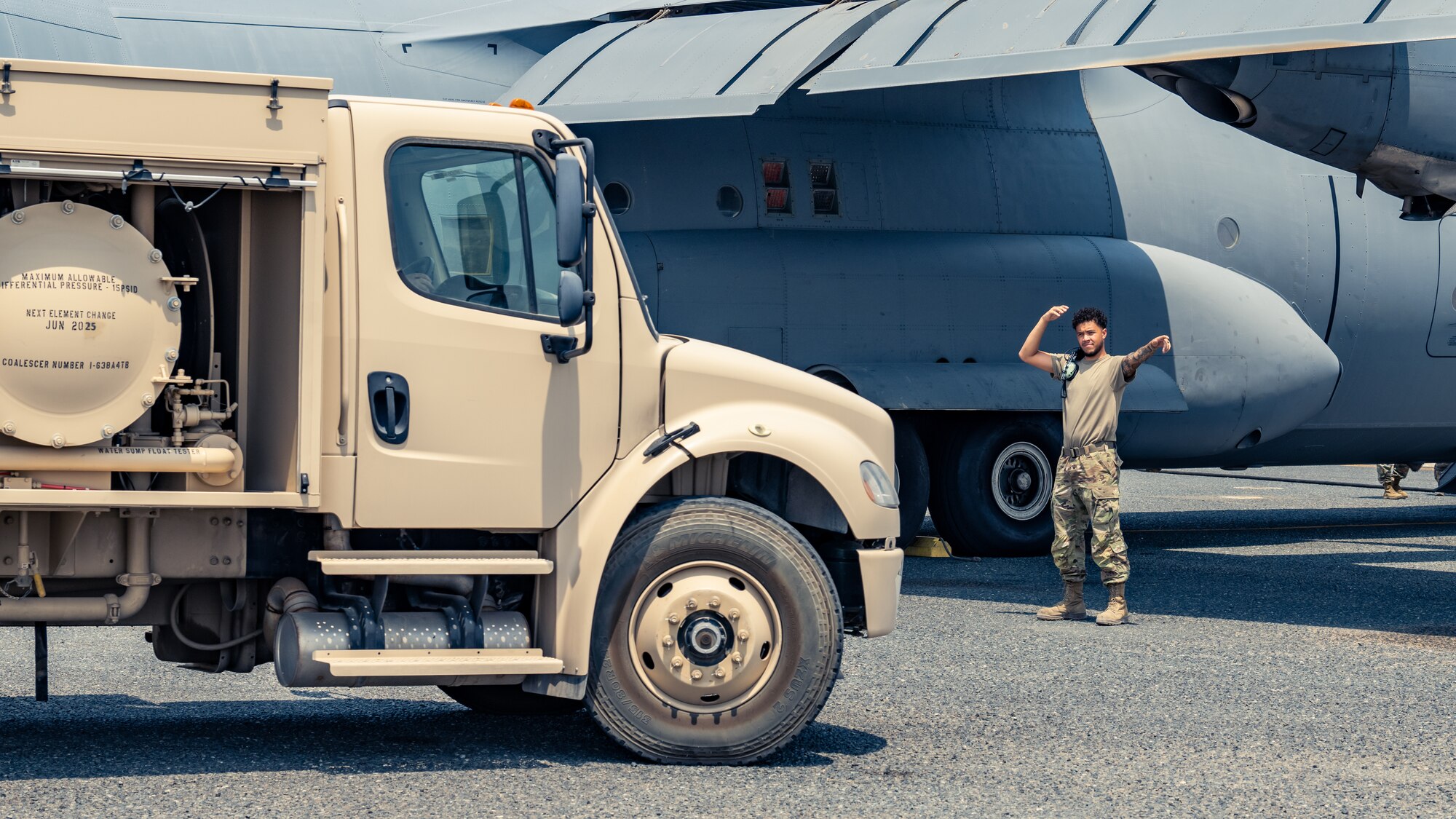 Senior Airman Miguel Frias, 386th Expeditionary Logistics Readiness Squadron fuels journeyman, directs a fuel truck into position during a training event with the 386th Expeditionary Aircraft Maintenance Squadron at Ali Al Salem Air Base, Kuwait, Aug. 22, 2023. Airmen from both squadrons trained each other and swapped roles for this event to ensure everyone remains multi-capable and ready to lend a hand in generating airpower wherever they are needed. (U.S. Air Force photo by Staff Sgt. Kevin Long)