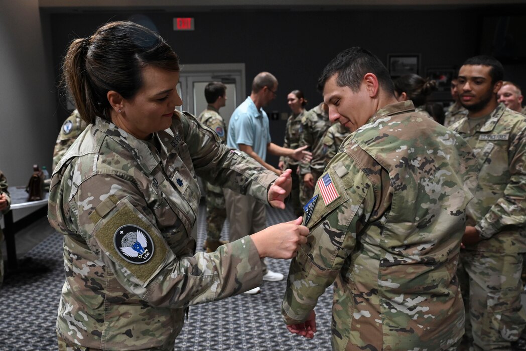 U.S. Space Force Lt. Col. Michelle Saffold, 71st Intelligence, Surveillance, and Reconnaissance Squadron commander, presents a patch to Spc. 1 Hayden Doglione before the Space Intelligence Fundamentals graduation at the Powell Event Center, Goodfellow Air Force Base, Texas, Aug. 22, 2023. Doglione was assigned to report to the 71st ISR squadron as his first operational assignment. (U.S. Air Force photo by Airman 1st Class Madison Collier)