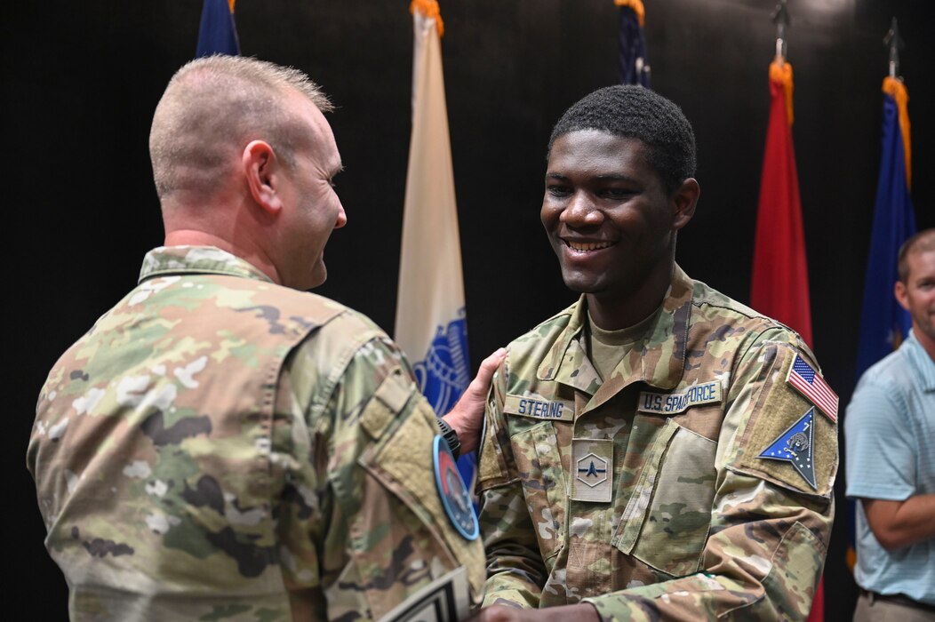 U.S. Space Force Spc. 2 Demicheal Sterling receives a coin from Capt. Bobby Freeman, 533rd Training Squadron Detachment 1 commander, during the Space Intelligence Fundamentals graduation at the Powell Event Center, Goodfellow Air Force Base, Texas, Aug. 22, 2023.Sterling received the Top Critical Thinker certificate upon completion of the course. (U.S. Air Force photo by Airman 1st Class Madison Collier)