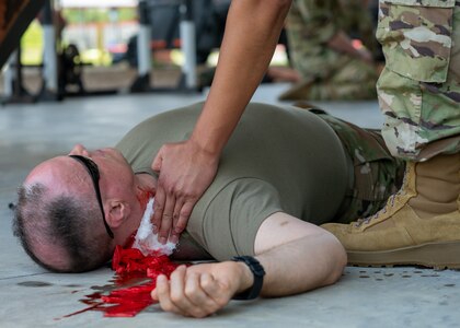 An Airman from the 138th Medical Group assesses and cares for a simulated injury on Senior Master Sgt. Gary Cathey, 138th Medical Group superintendent for health services, during Tactical Combat Casualty Care (TCCC) training in Perry, Fla., July 20, 2023. Part of TCCC training is having Airmen assess which injured personnel can be saved and those who cannot in order to prioritize those with a higher chance of survival versus those who need more immediate help. (Oklahoma National Guard Photo by Airman 1st Class Addison Barnes)