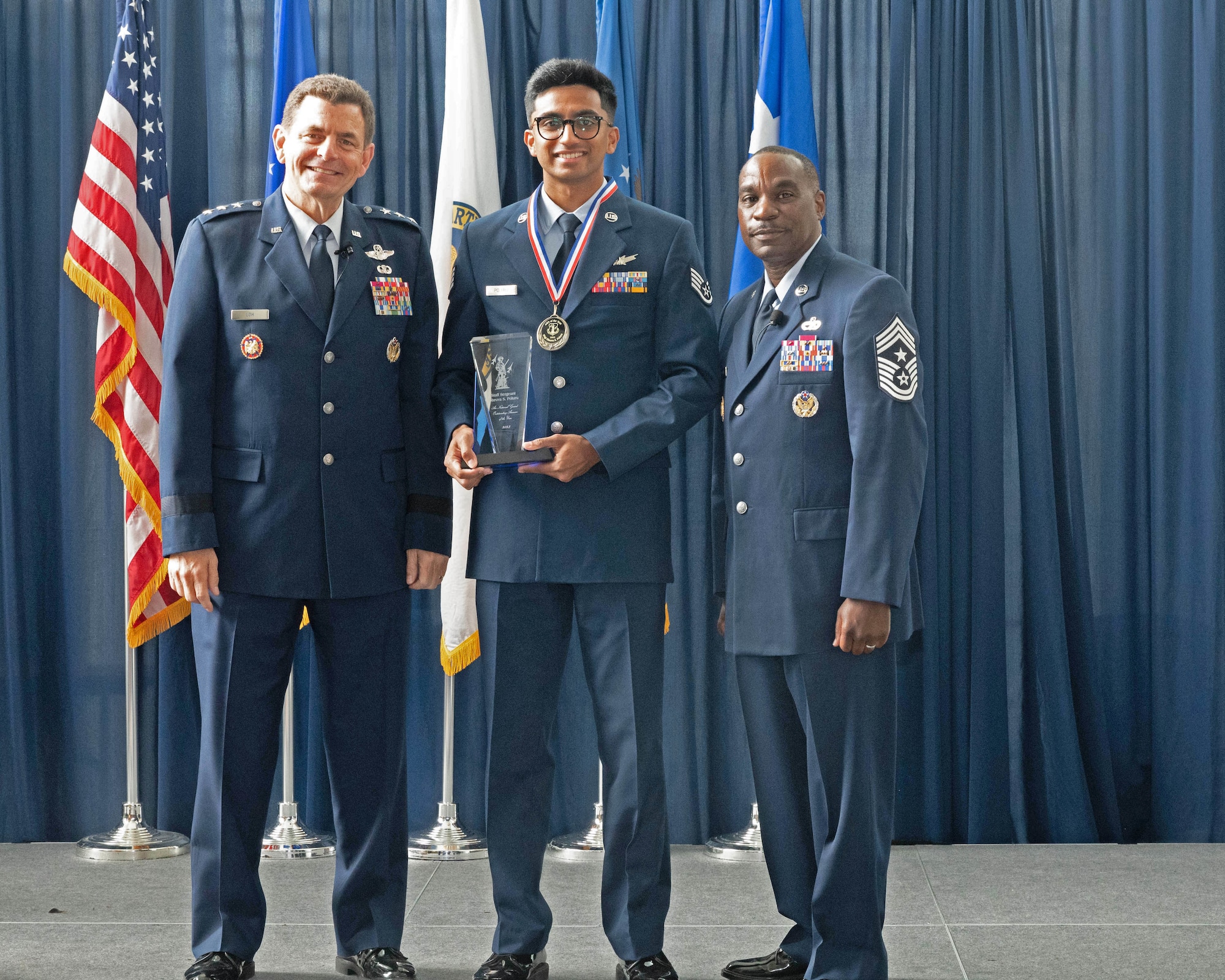 U.S. Air Force Staff Sgt. Dhruva Poluru, center, space system operations, 222nd Command and Control Squadron, 107th Attack Wing, New York National Guard poses with Lt. Gen. Michael Loh, left, director, Air National Guard and Chief Master Sgt. Maurice Williams, command chief, ANG, after being recognized as the Outstanding Airman of the Year during a ceremony at the Air National Guard Readiness Center, Joint Base Andrews, Maryland, Aug. 24, 2023.