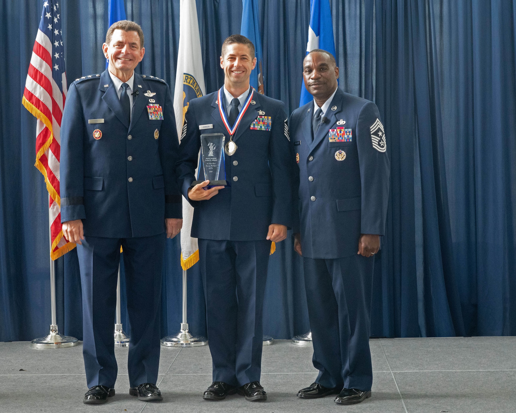 U.S. Air Force Master Sgt. Joshua Johnson, center, first sergeant, 233rd Security Forces Squadron, 140th Wing, Colorado National Guard poses with Lt. Gen. Michael Loh, left, director, Air National Guard and Chief Master Sgt. Maurice Williams, command chief, ANG, after being recognized as the ANG’s Outstanding First Sergeant of the Year at the Air National Guard Readiness Center, Joint Base Andrews, Maryland, Aug. 24, 2023.