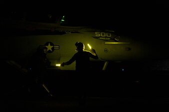 A sailor inspects an E/A-18G Growler on the flight deck aboard USS Nimitz (CVN 68).