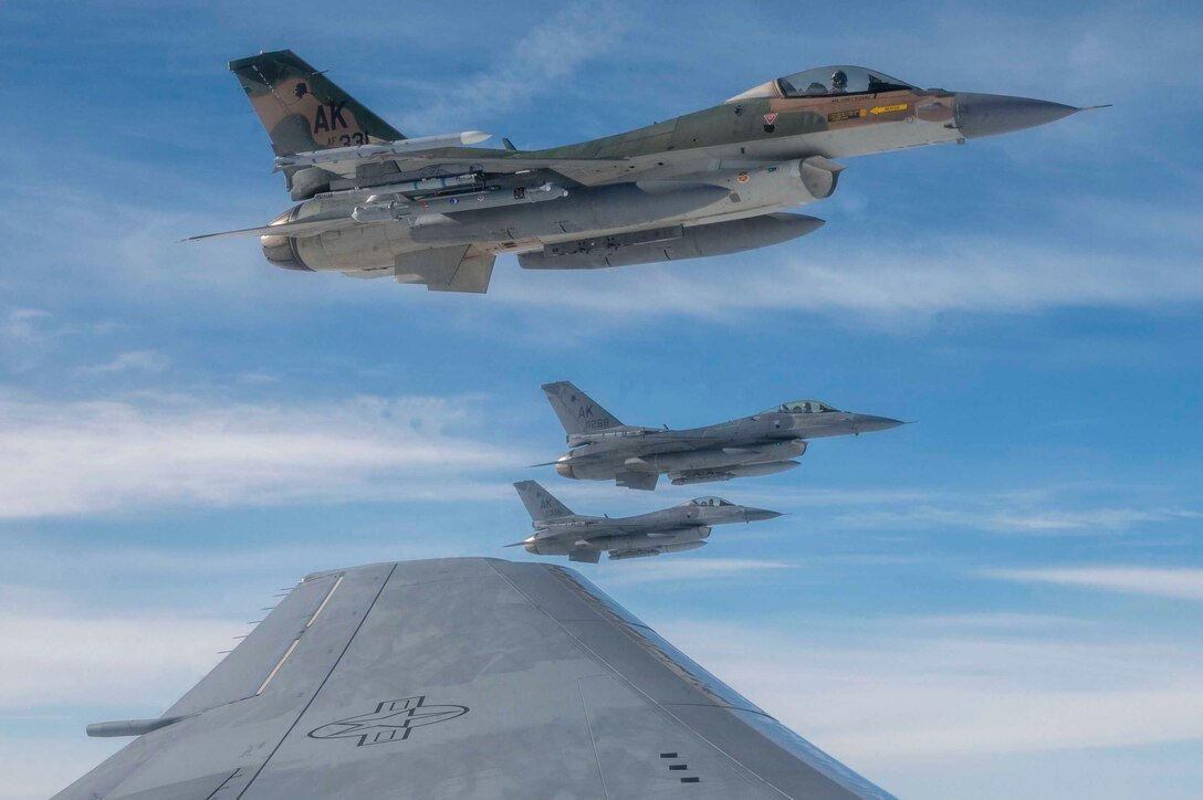 Four military aircraft fly next to each other during daylight.