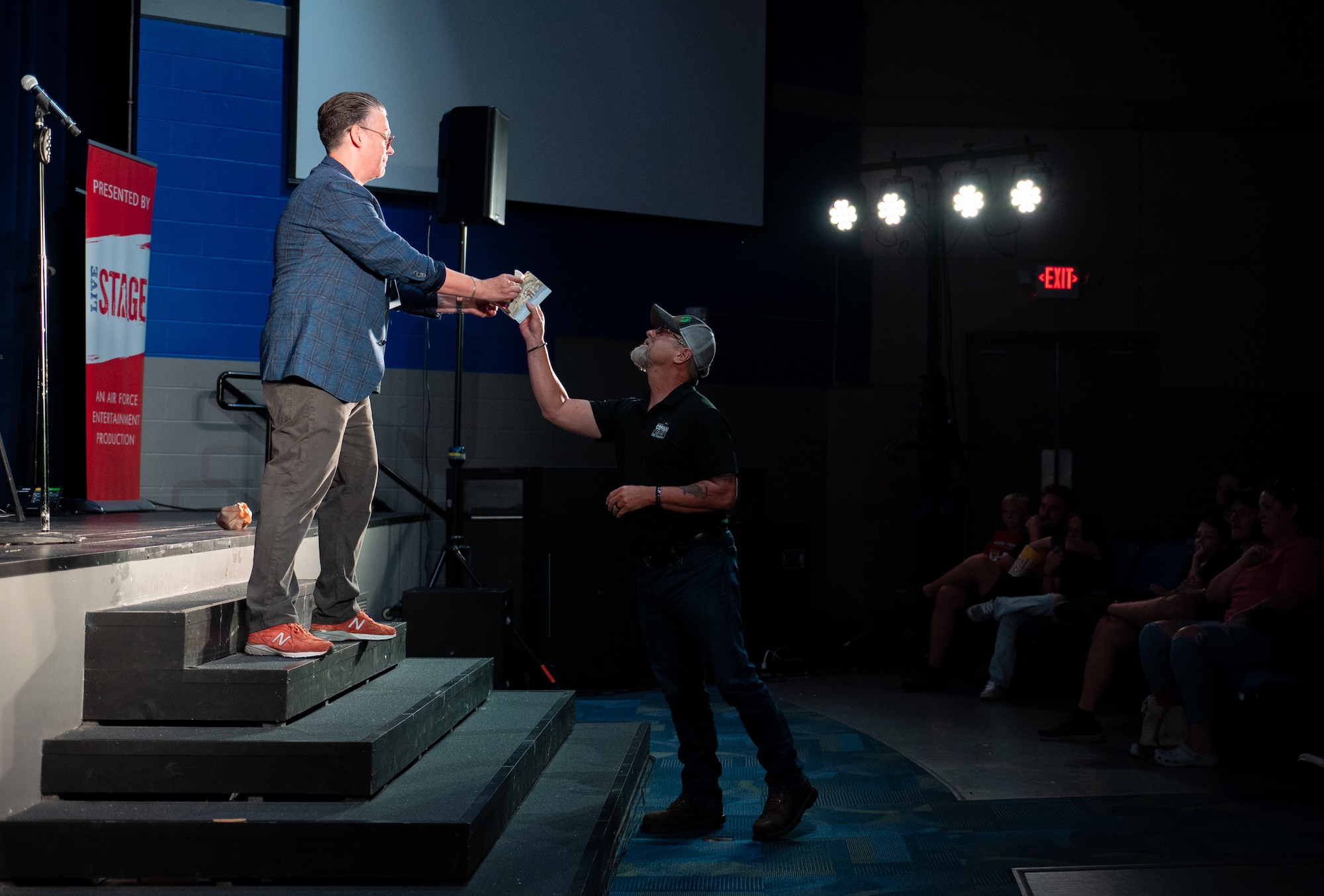 A volunteer from the crowd grabs a prop from Derek Hughes, a comedian, during the Smash Up Comedy night at Moody Air Force Base, Georgia, Aug. 17, 2023. The Smash Up Comedy tour was an on-base family event which dazzled the audience with comedy, magic, and music. (U.S. Air Force photo by Airman 1st Class Leonid Soubbotine)