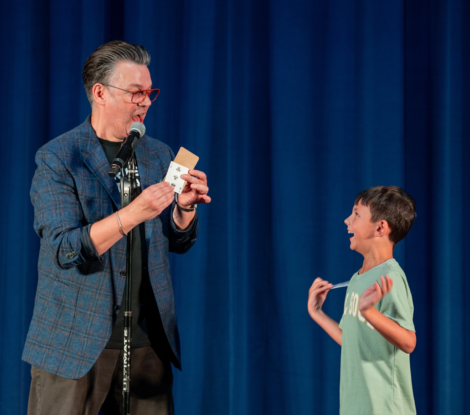 Derek Hughes, a comedian, reveals a card to a young participant during the Smash Up Comedy night at Moody Air Force Base, Georgia, Aug. 17, 2023. The Smash Up Comedy tour was an on-base family event which dazzled the audience with comedy, magic, and music. (U.S. Air Force photo by Airman 1st Class Leonid Soubbotine)