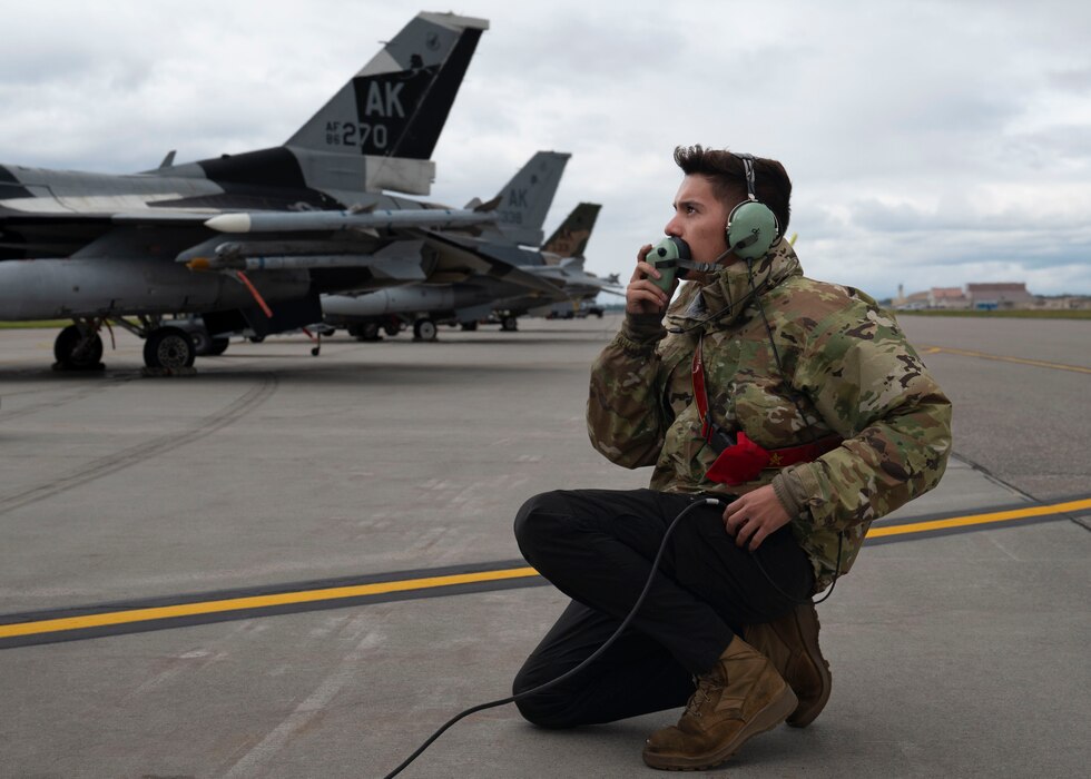 U.S. Air Force Airman 1st Class Tanner Davis, 354th Aircraft Maintenance Squadron crew chief, communicates with a pilot during preflight checks while participating in Red Flag-Alaska 23-3 at Eielson Air Force Base, Alaska, Aug. 17, 2023. Red Flag focuses on the Pacific Theater by advancing the training towards mission sets in the maritime domain. (U.S. Air Force photo by Senior Airman Megan Estrada)