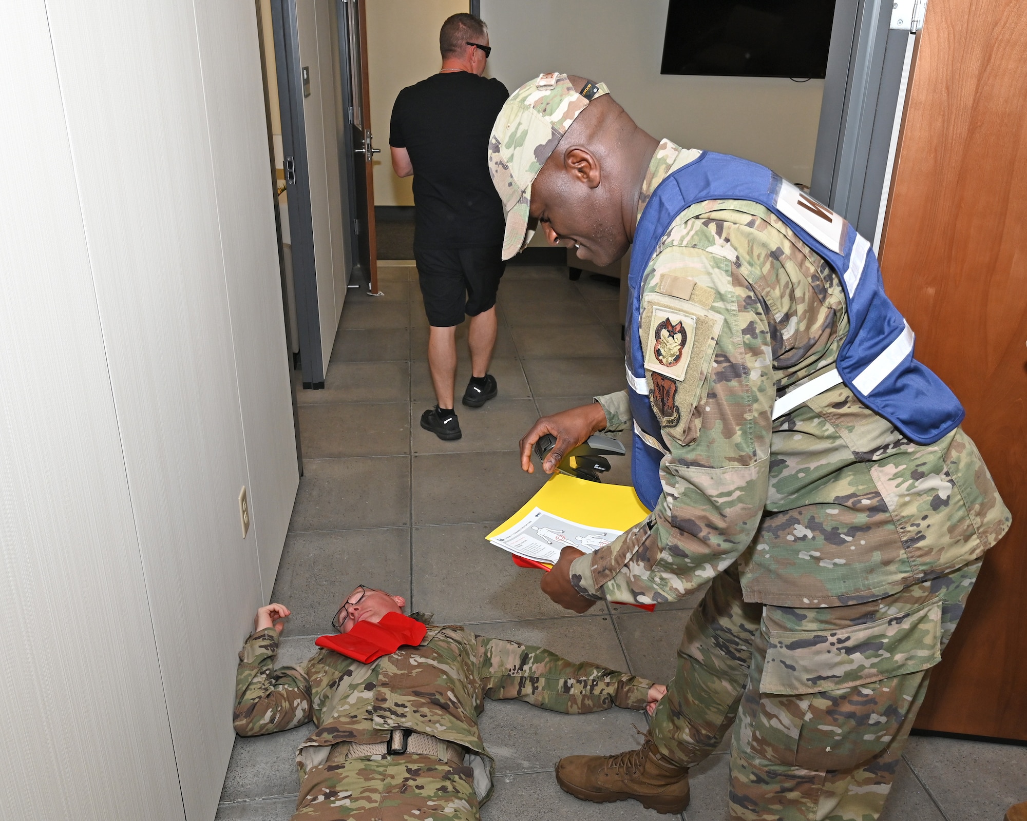 U.S. Air Force Staff Sgt. Geoffrey Elungata, 175th inspections coordinator, places an inject card onto a simulated victim of an active shooter during an exercise at Martin State Air National Guard Base, Middle River, Md., Aug. 25, 2023.