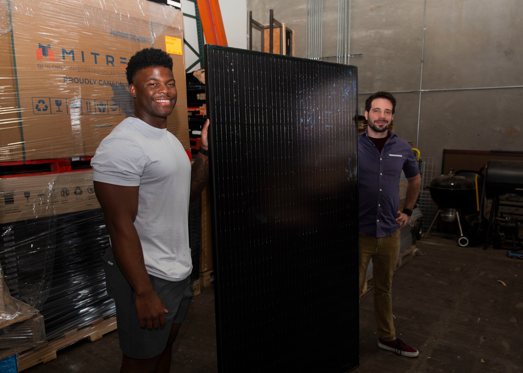 U.S. Air Force Staff Sgt. Donte Alexander, 372nd Training Squadron avionics instructor (left), and Matt Hoffman, On Point Solar Power director of operations, stand with a solar panel Aug. 23, 2023,