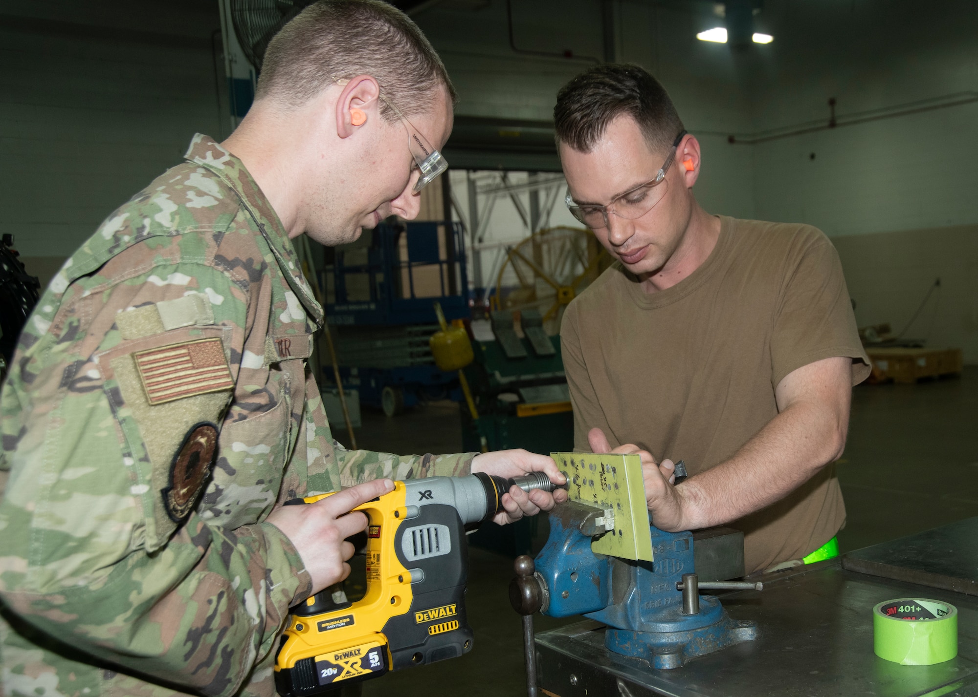 Two men use a tool for riveting