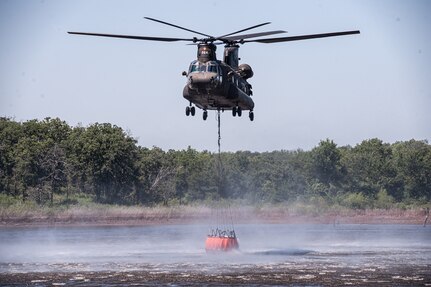 An Oklahoma Army National Guard CH-47 Chinook helicopter crew fills a water bucket during wildfire fighting training in August 2015. (Oklahoma National Guard photo by Staff Sgt. Christopher Bruce)