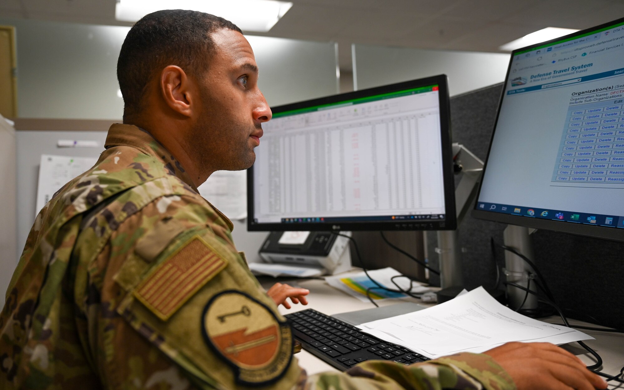 Uniformed member sits at computer.