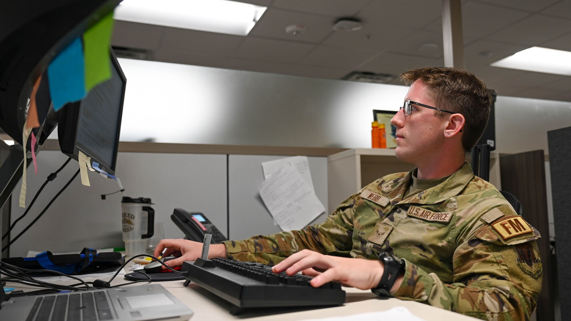 Uniformed member sits at computer