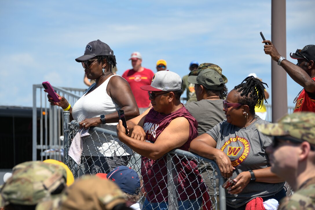 People in bleachers use their phones to take pictures.