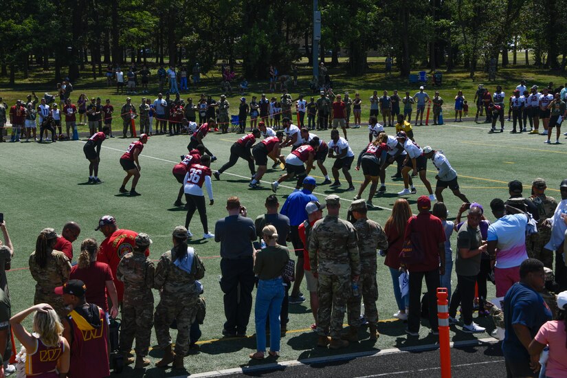 People and spectators gather at a football field.