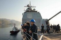 Boatswain’s Mate 2nd Glen Gonzalez, assigned to the Ticonderoga-class guided missile cruiser USS Normandy (CG 60), center right, mans the rails as the ship pulls in Aksaz Naval Base, Turkiye, Aug. 26, 2023. Normandy is part of the Gerald R. Ford Carrier Strike Group and is on a scheduled deployment in the U.S. Naval Forces Europe area of operations, employed by Sixth Fleet to defend U.S., allied, and partner interests. (U.S. Navy photo by Mass Communication Specialist 2nd Class Malachi Lakey)