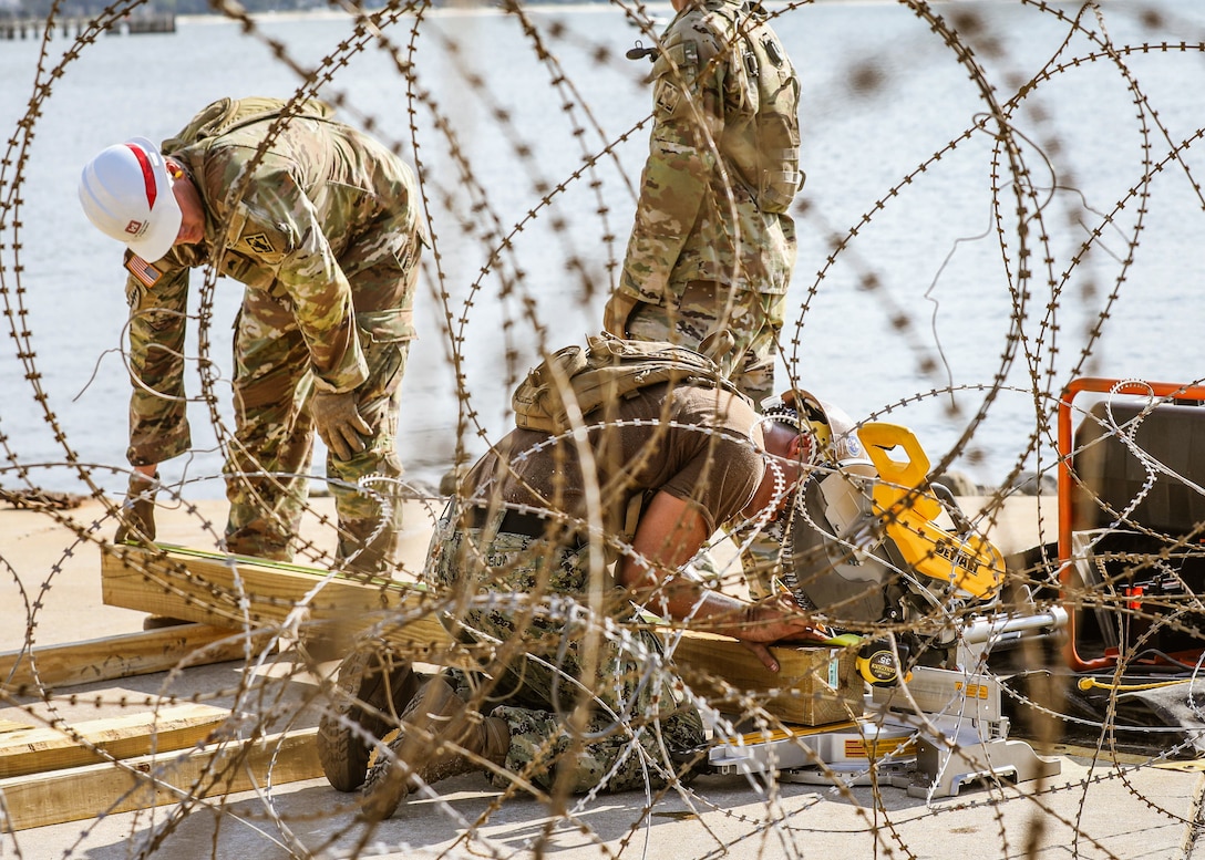 U.S. Navy Seabees assigned to Naval Mobile Construction Battalion (NMCB) 11 and U.S. Army Soldiers assigned to the 526th Engineer Company, 92nd Engineer Battalion, 20th Engineer Brigade out of Fort Stewart, Ga., measure and cut timber during an expeditionary construction exercise in the Port of Gulfport, Miss., August 8, 2023.