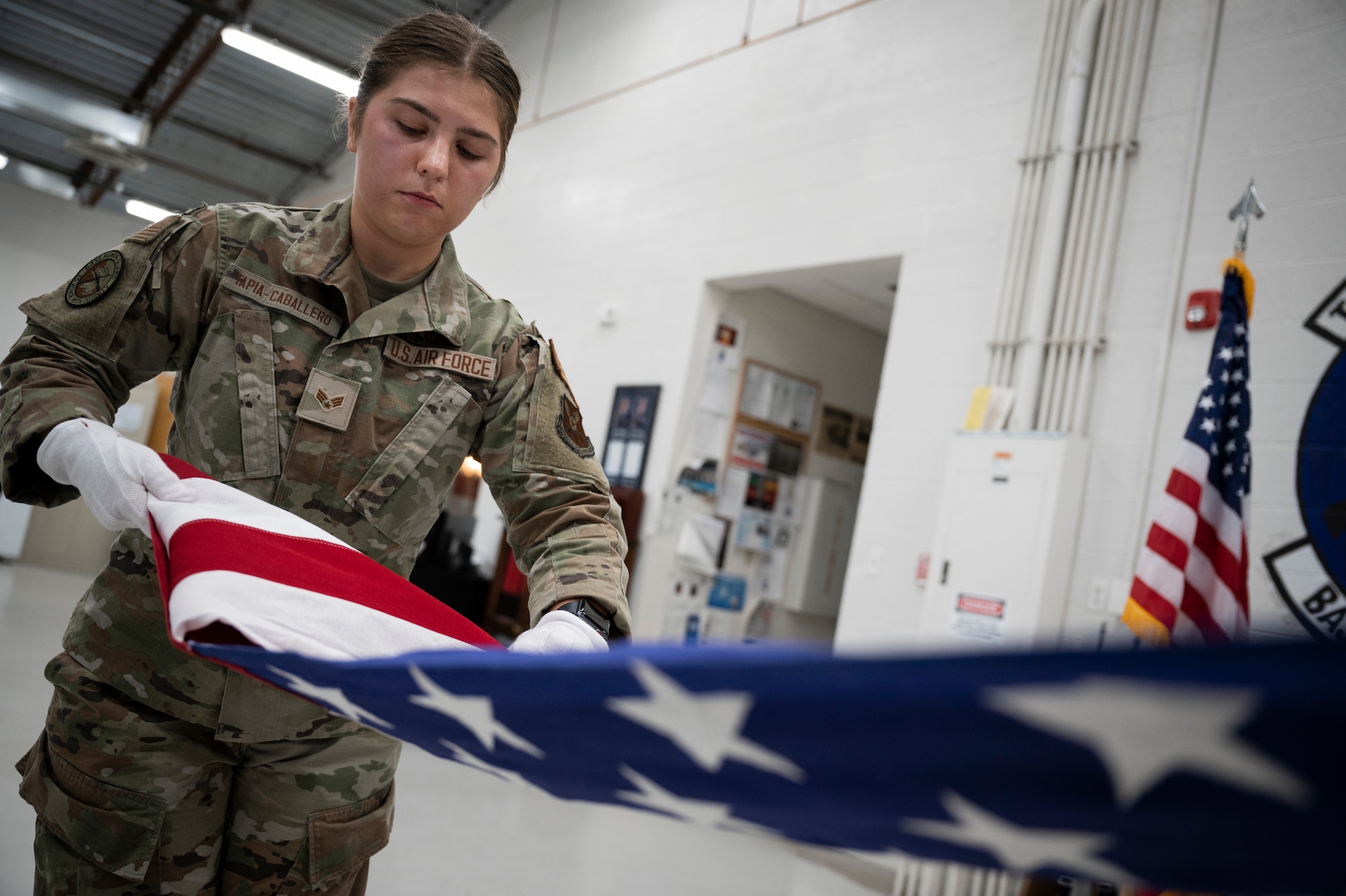 A woman in military uniform is shown folding a U.S. flag.