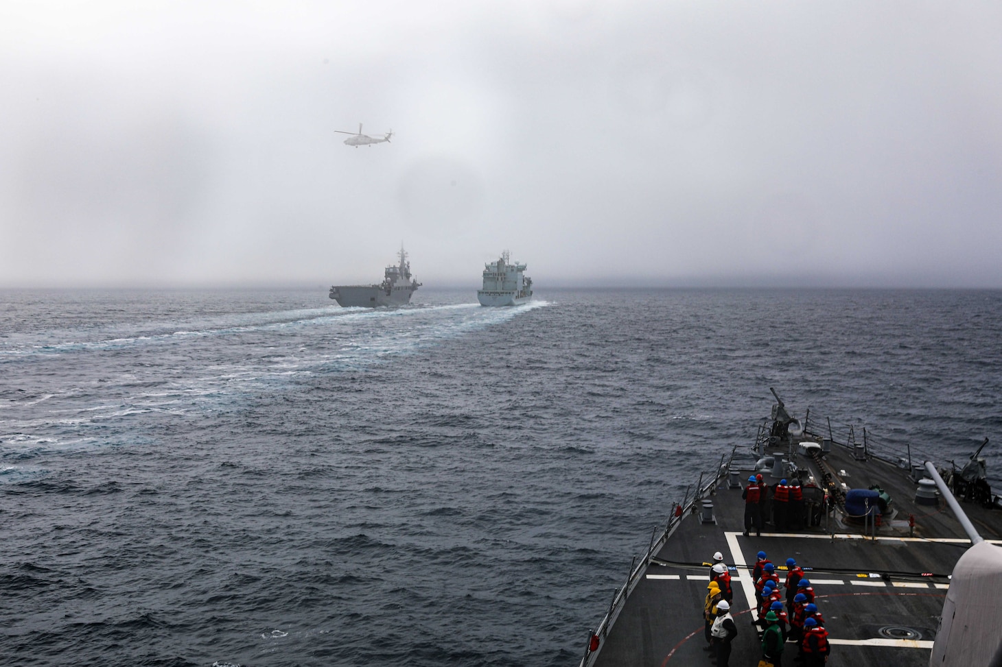 Royal Canadian Navy replenishment ship MV Asterix conducts a replenishment-at-sea with the Japanese Maritime Self-Defense Force JS Hyūga (DDH-181), while the Arleigh Burke-class guided-missile destroyer USS Benfold (DDG 65) stands by to conduct a replenishment-at-sea in the North Pacific Ocean on Aug. 25.