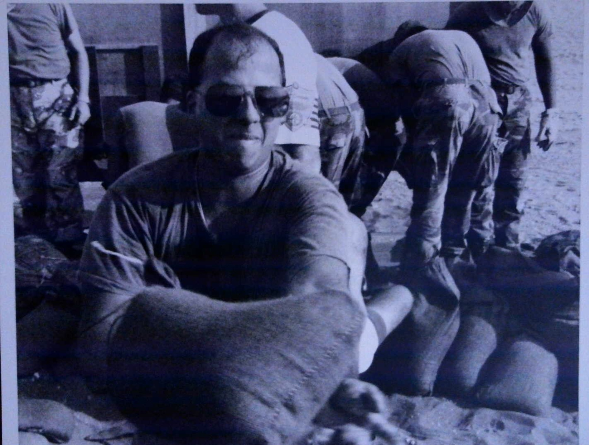 A historic photo of a service member moving sandbags.