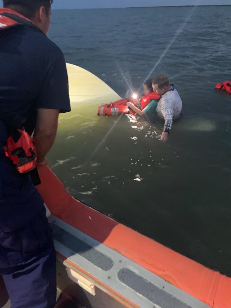 A Coast Guardsman with Coast Guard Station Gulfport gives instructions to two boaters in distress approximately 3 miles southwest of Cat Island, Mississippi, August 27, 2023.