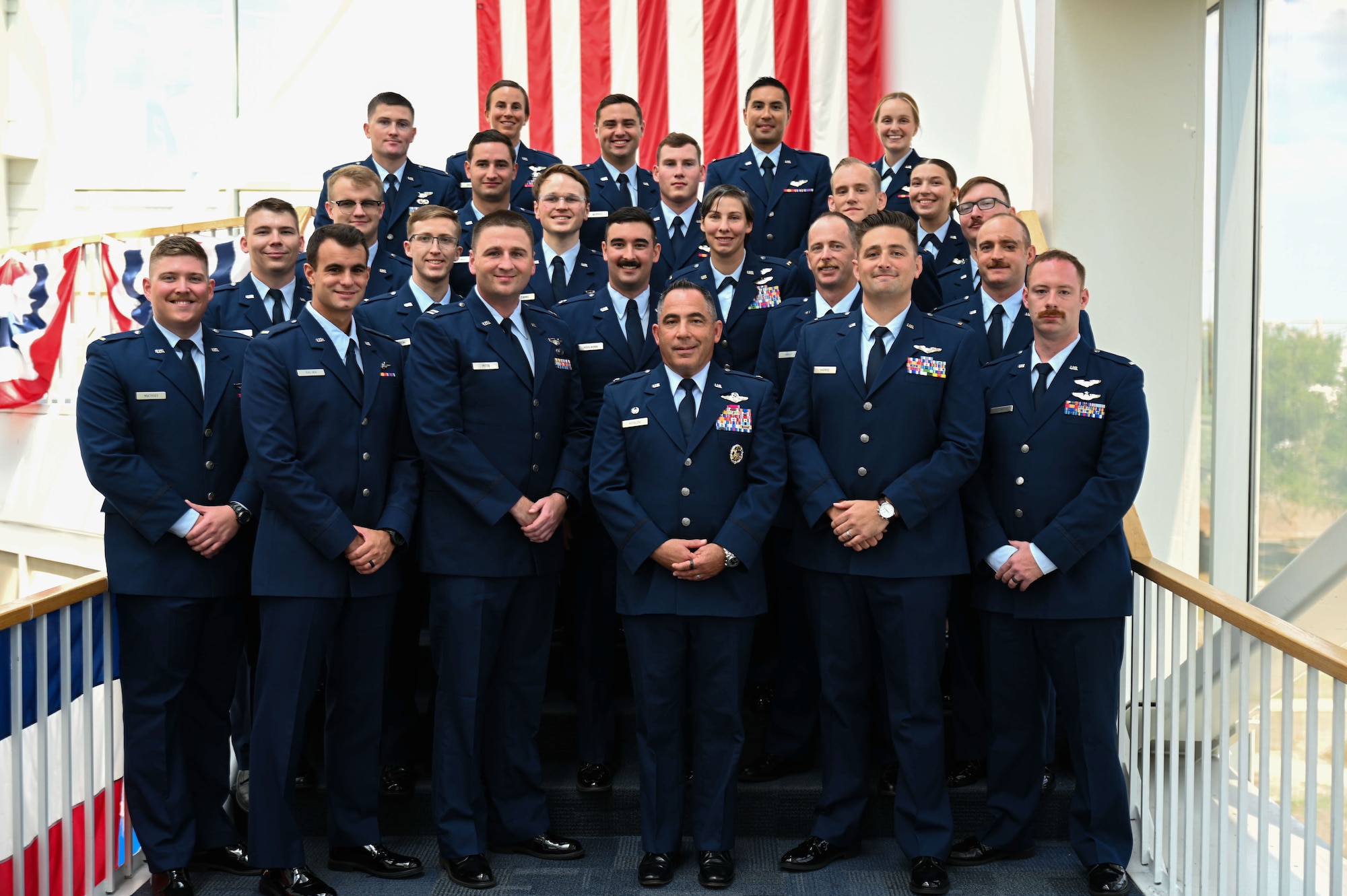 U.S. Air Force Col. Josh Koslov, 350th Spectrum Warfare Wing commander, center, poses for a photo with the graduating class at the Undergraduate Combat Systems Officer Training graduation at National Naval Aviation Museum, Naval Air Station Pensacola, Fla., Aug. 25, 2023. The 479th Flying Training Group conducts combat systems officer training for newly commissioned U.S. Air Force officers. (U.S. Air Force photo by Capt. Benjamin Aronson)