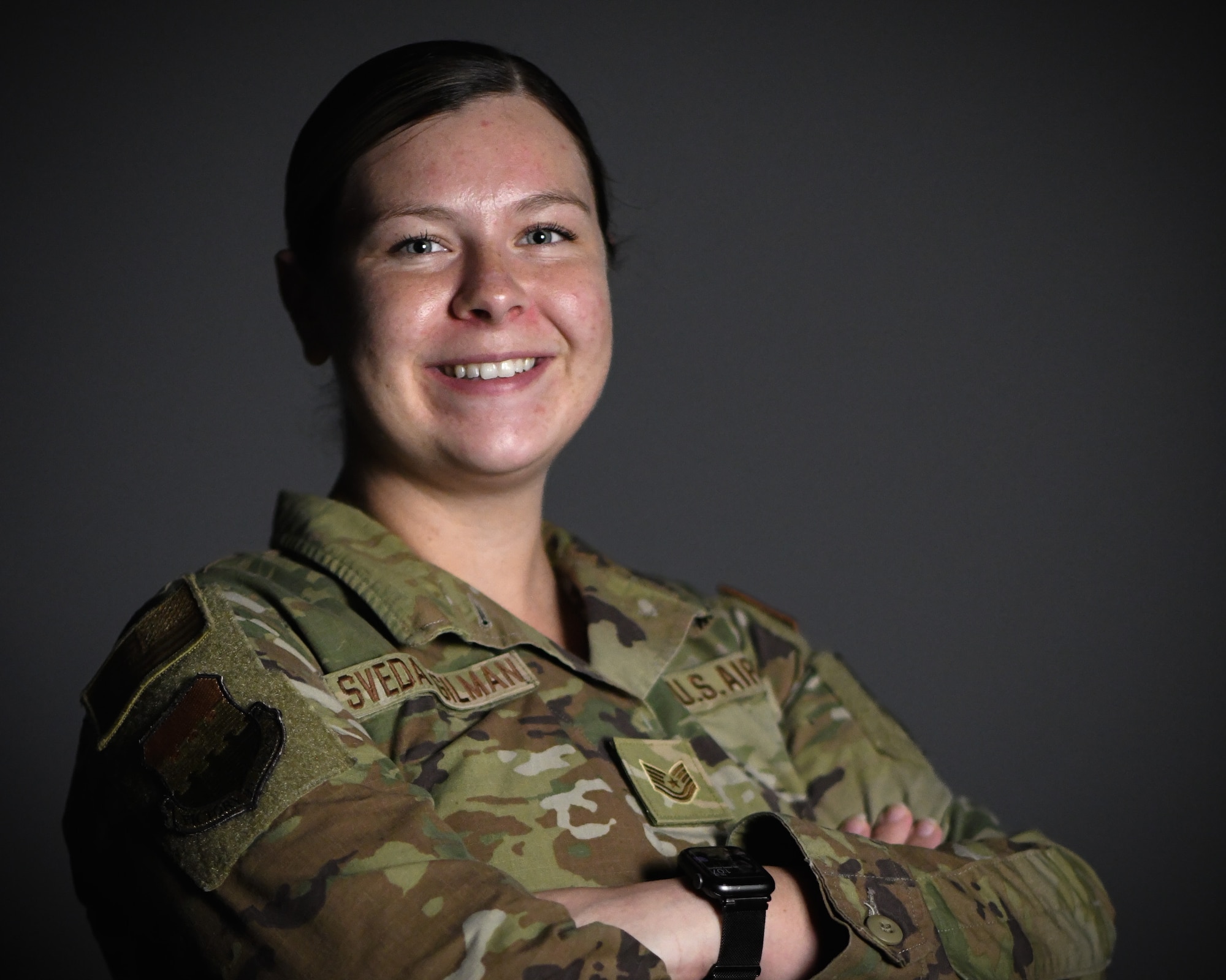 Military member poses for a photo against dark grey background.