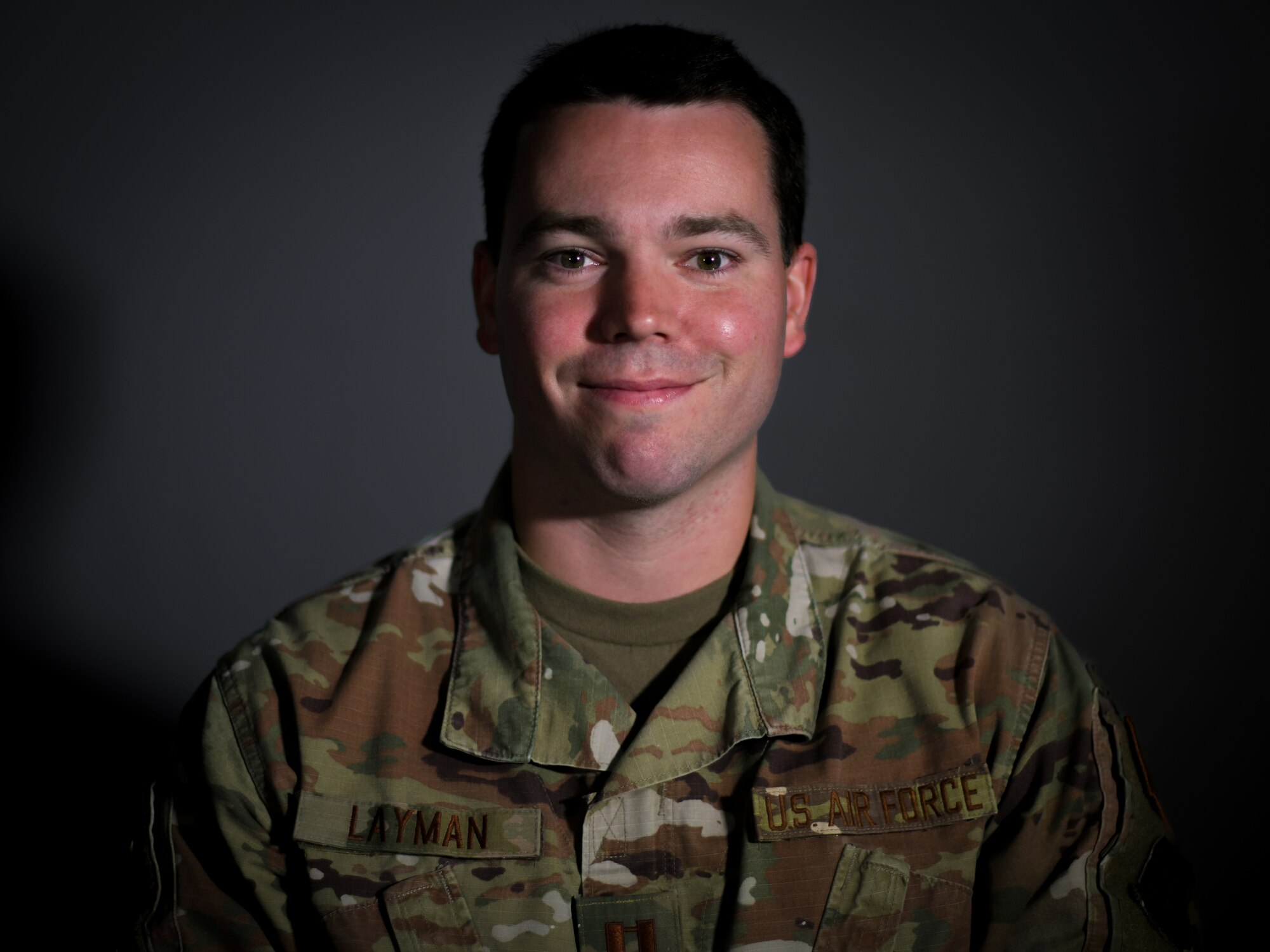 Military member poses for a photo against dark grey background.