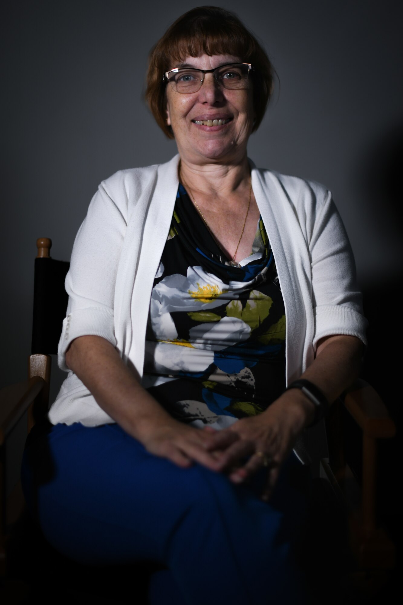 Woman poses for a photo against a dark grey background.