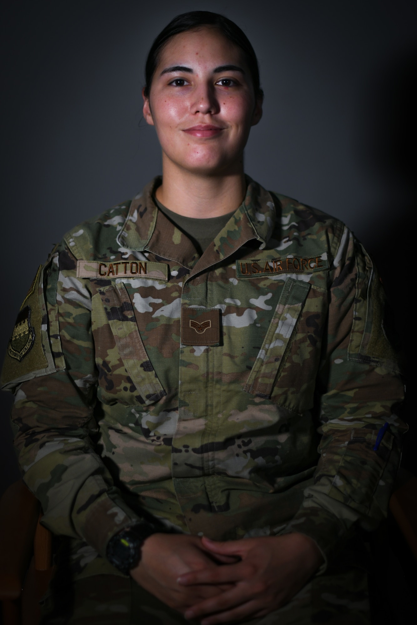 Military member poses for a photo against dark grey background.