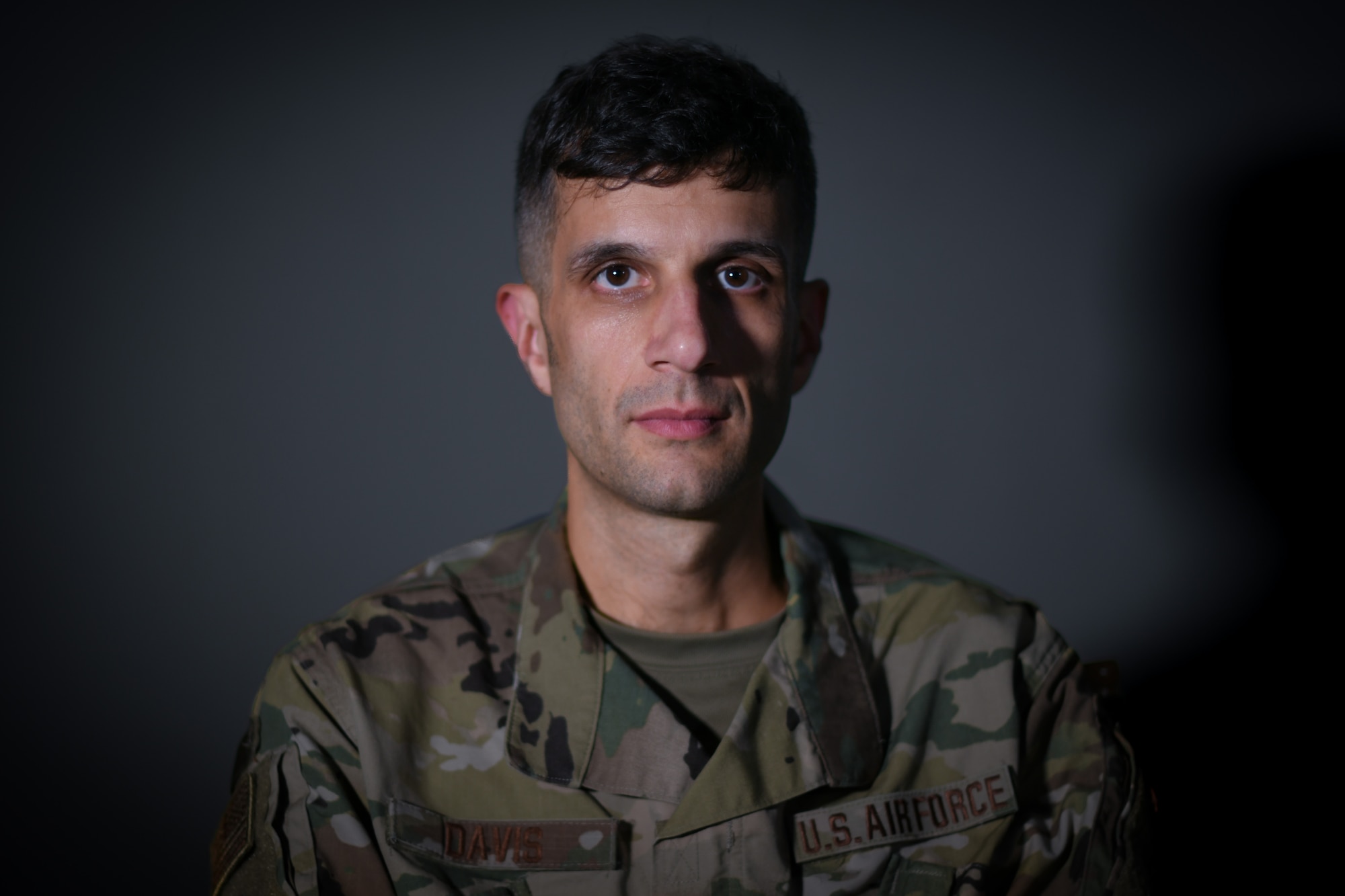 Military member poses for photo against dark grey background.