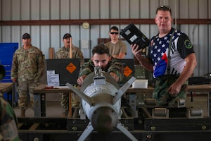 U.S. Air Force Airmen from Osan Air Base, Republic of Korea, 51st Munitions Squadron, ensure the forward strake of the GBU-38 munition is aligned while building munitions for the Air Force Combat Operations Competition, Aug. 22, 2023, at Beale Air Force Base, California.