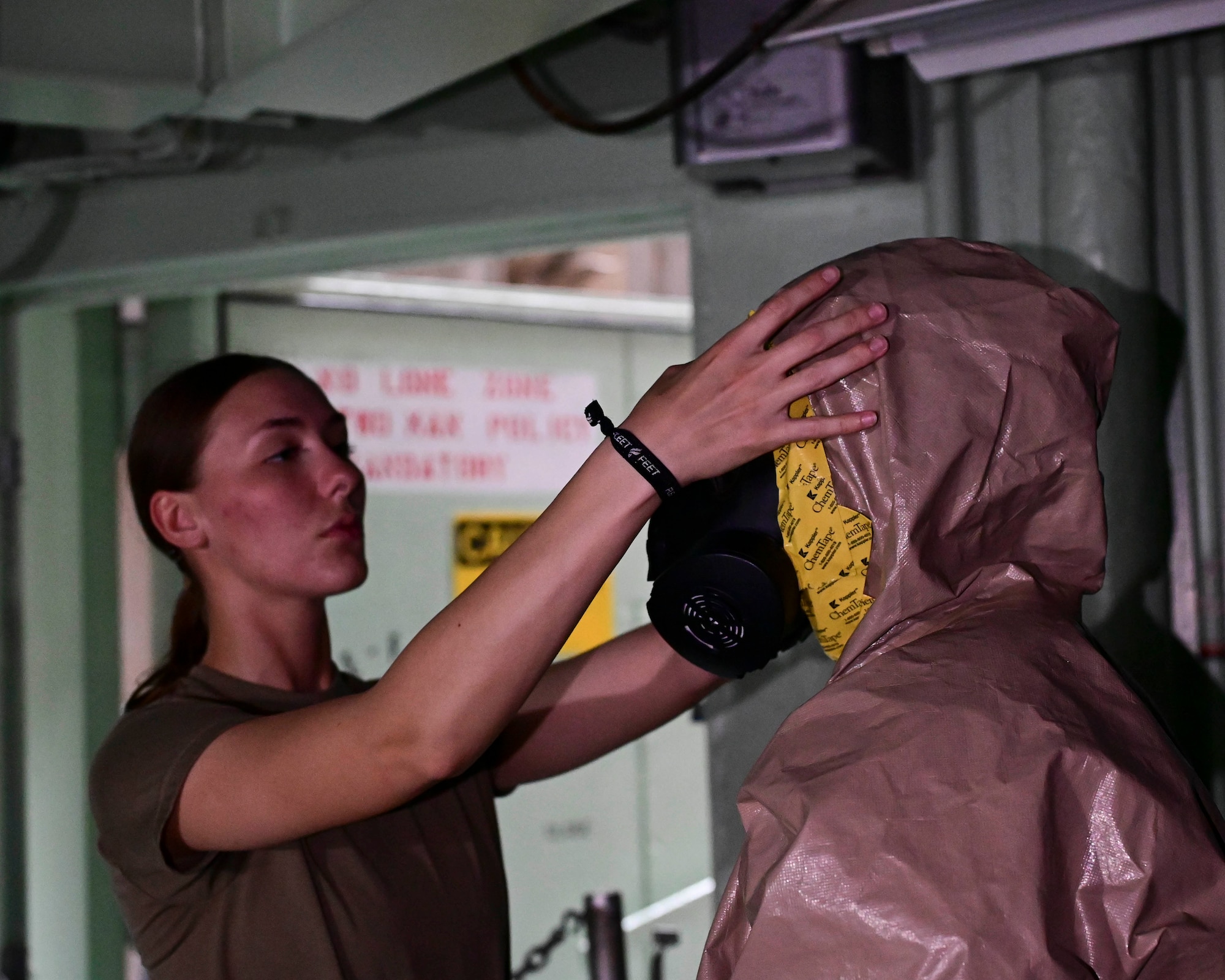 Woman seals chemical suit of co-worker