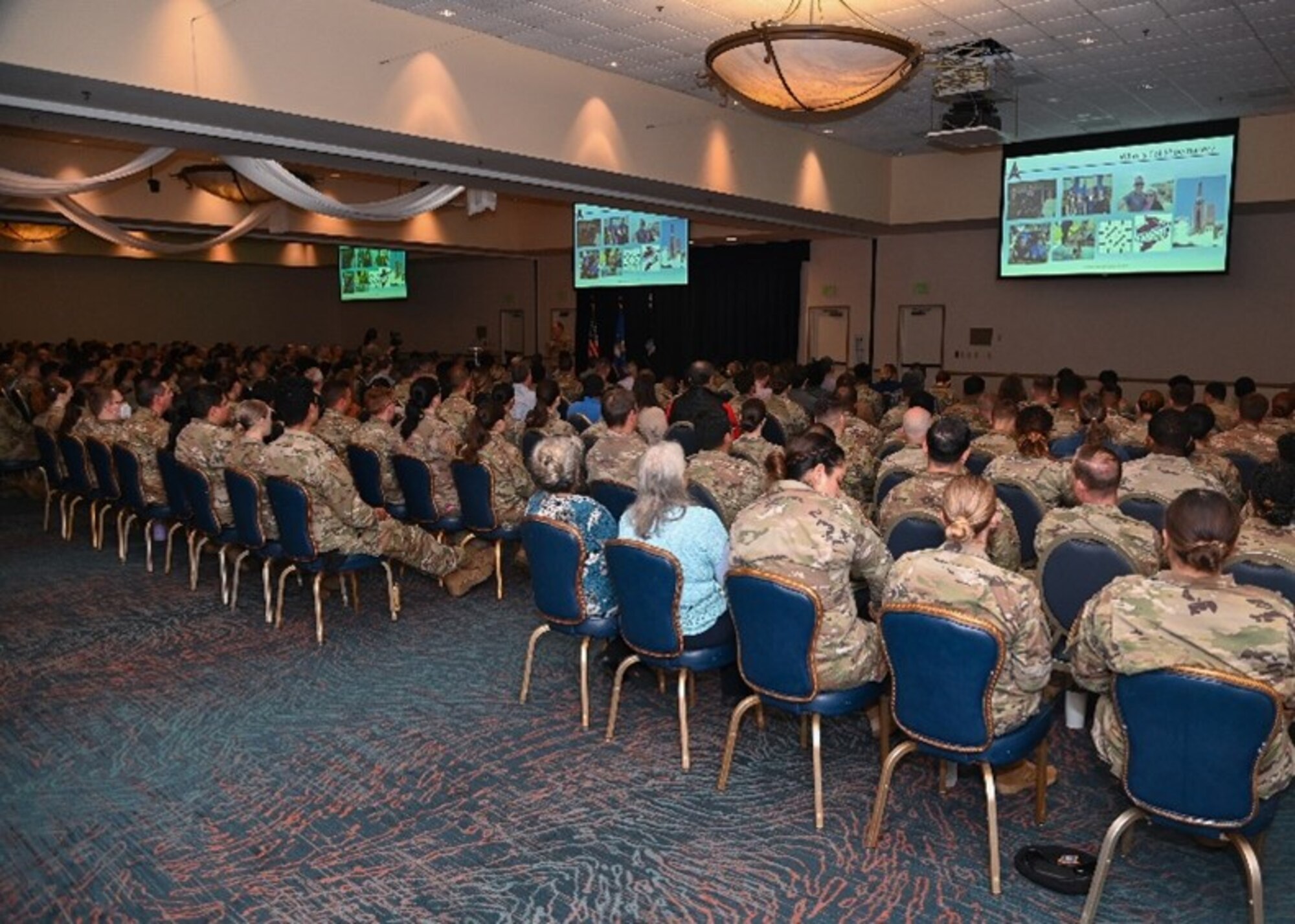 airmen and guardians sit down listening to commander at all-call