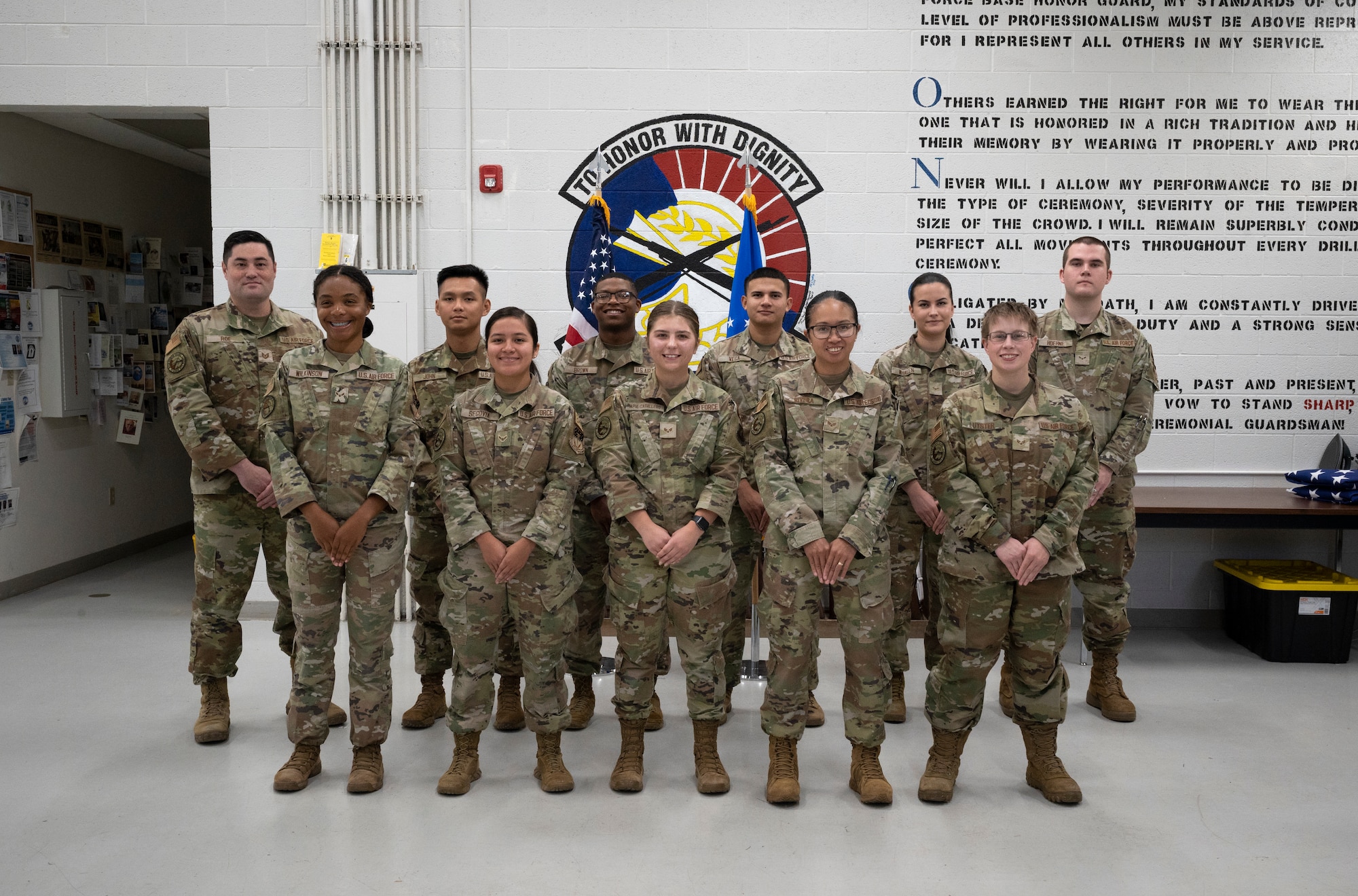 A group of military uniformed personnel stand in two rows for a group photo.