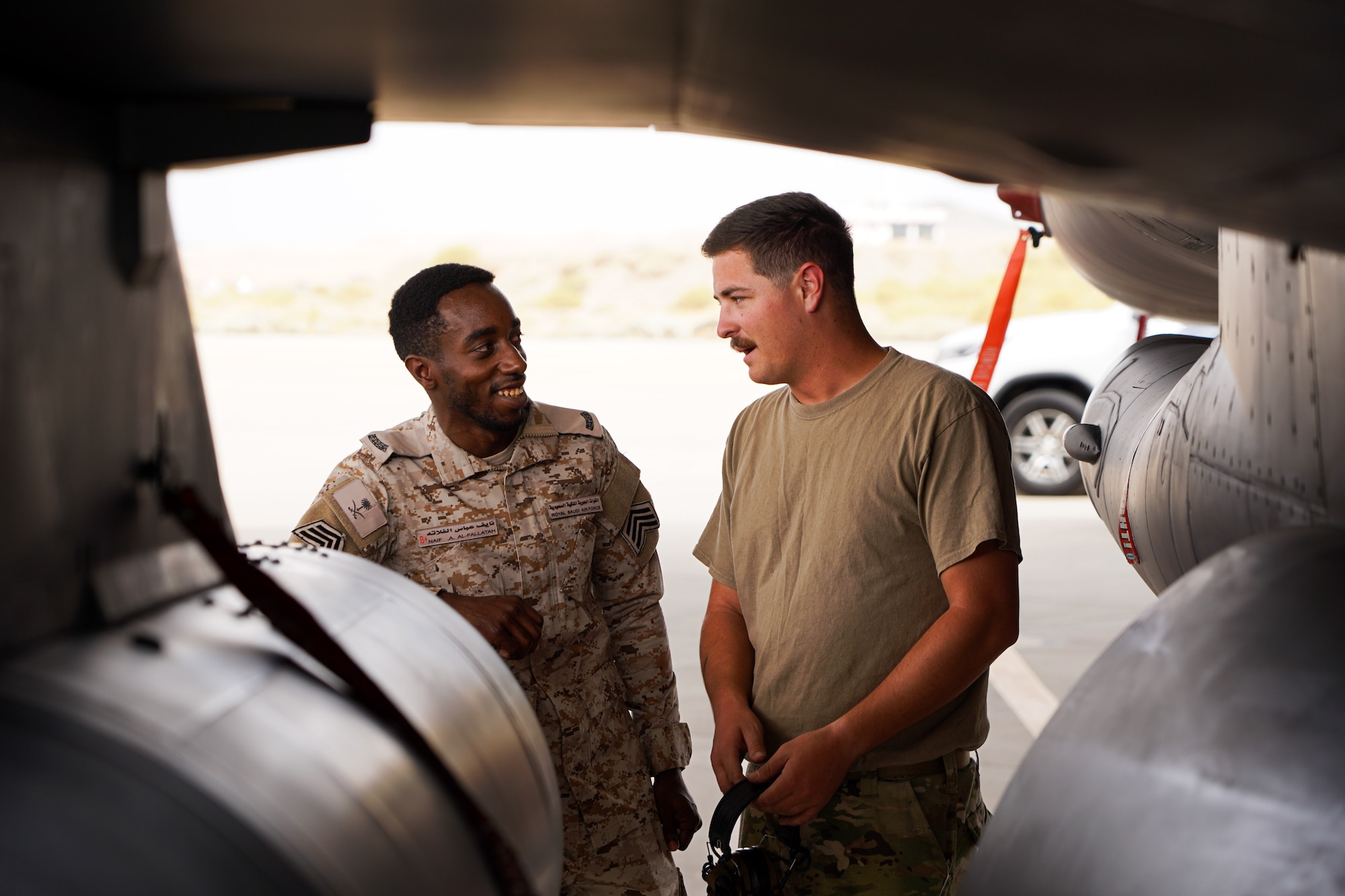 U.S. Air Force Staff Sgt. Jonathan Miles (right), 125th Expeditionary Fighter Generation Squadron (EFGS) crew chief, speaks with a maintainer from the Royal Saudi Air Force (RSAF) during Operation Agile Spartan, Kingdom of Saudi Arabia, Aug. 21, 2023. During the operation, RSAF and 125th EFGS maintainers toured each other's aircraft to see how each partner nation performs their maintenance duties. Agile Spartan 23.2 is a multinational operation aimed at strengthening interoperability, improving response capabilities, and furthering security cooperation initiatives throughout the U.S. Central Command area of responsibility. (U.S. Air Force photo by Tech. Sgt. Alexander Frank)