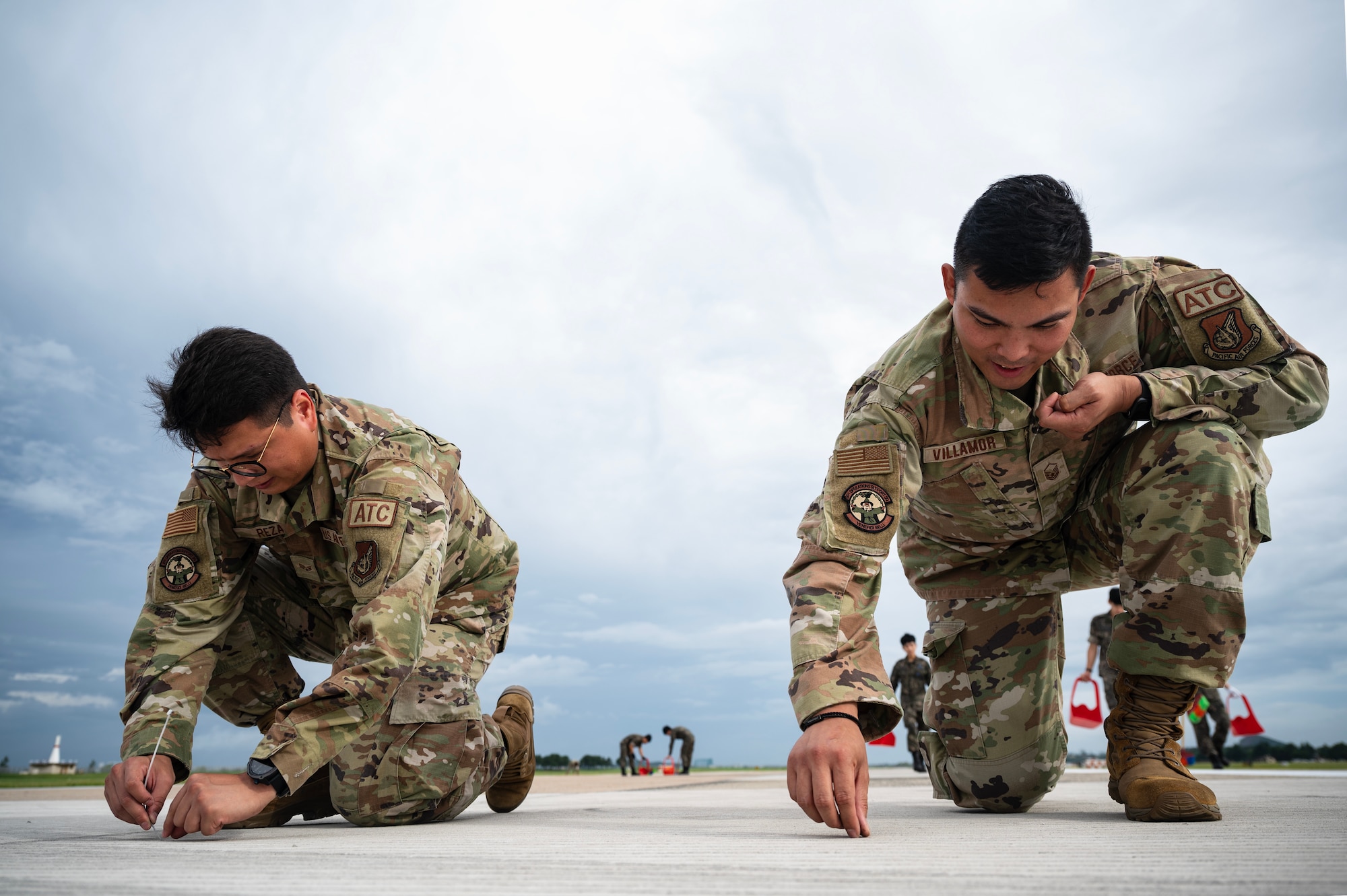 Master Sgt. Michael Villamor and Senior Airman Francisco Reza collect debris off the flightline in preparation for the return of  F-16s and KF-16 Fighting Falcons.