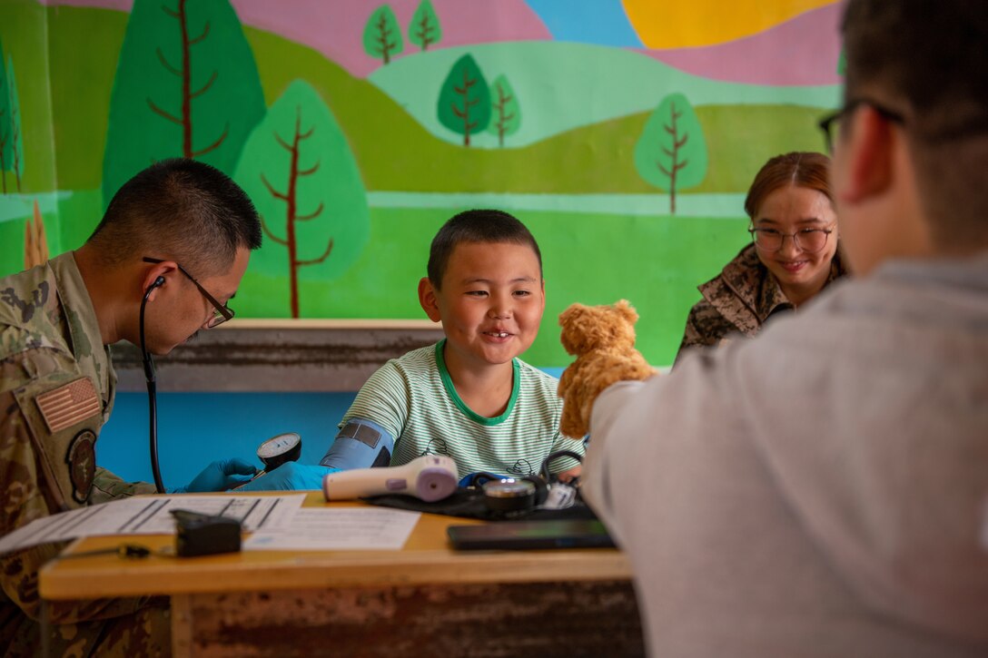 A young boy laughs at a hand toy as he gets his blood pressure checked.