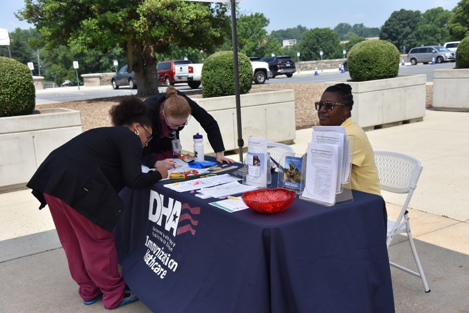 DHA worker at information table about immunizations