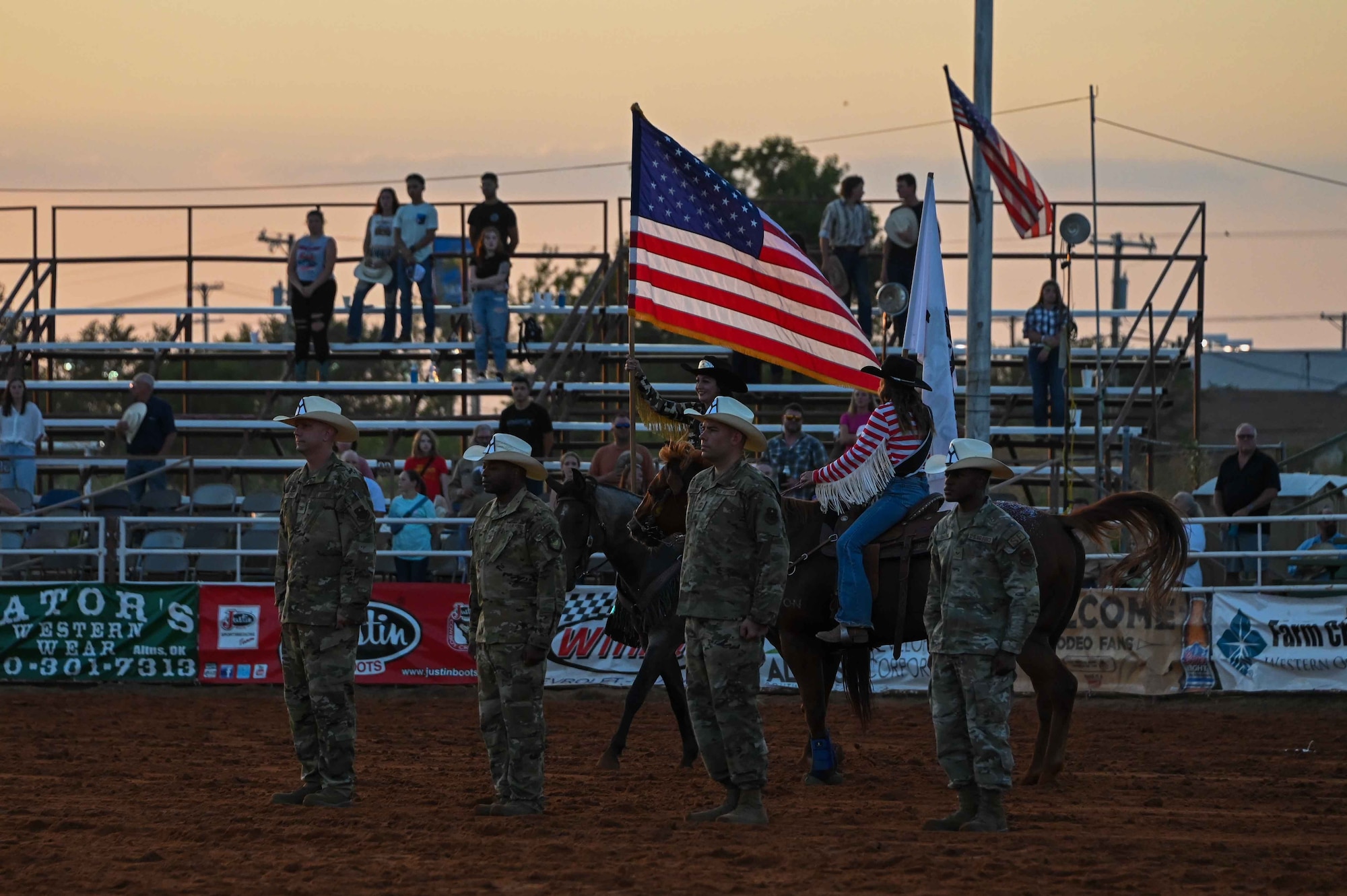 Airmen from the 97th Air Mobility Wing stand at attention during the playing of the national anthem at the Great Plains Stampede Rodeo in Altus, Oklahoma, August 24, 2023. During Military Appreciation Night, the rodeo honored the wing command team and Senior Airman Aaron Darling, 97th Security Forces installation entry controller, who represented all the Airmen of Altus Air Force Base. (U.S. Air Force photo by Airman 1st Class Kari Degraffenreed)
